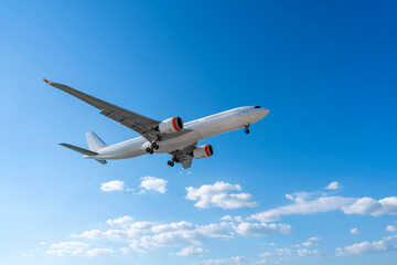 Airplane jet with landing gear down in the sky above the clouds flight journey sun