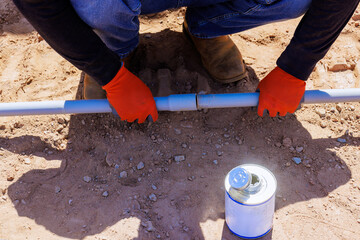Contractor in gloves connects two electrical plastic pipes on construction site with during foundation work