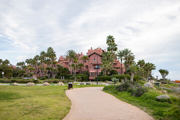 Obraz premium Boulevard path along Mediterranean sea in Spain with real estate luxury condominium of Tikitano with palm trees in the background
