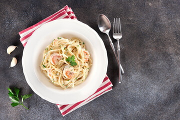 Italian shrimp pasta with cream sauce and parsley on dark background. Copy space, top view. Italian food