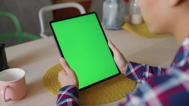 man holding tablet with green screen during coffee break, relaxed moment in cozy space, browsing project ideas, using app, watching videos, searching online, digital lifestyle and casual vibes indoors