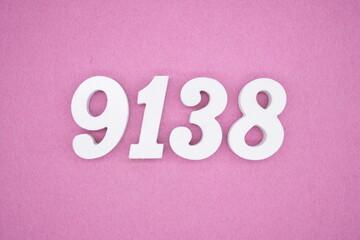The numbers are made of white painted wood and placed on a pink paper background.