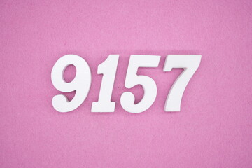 The numbers are made of white painted wood and placed on a pink paper background.