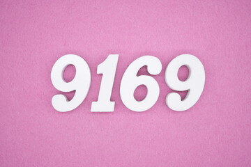 The numbers are made of white painted wood and placed on a pink paper background.