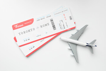 Travel agency. Flight tickets and plane model on light background, flat lay