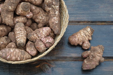 wicker basket with jerusalem artichoke harvest on wooden background. superfood topinambur