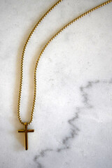 Religious Gold Cross Necklace on White Marble Background with Text Space