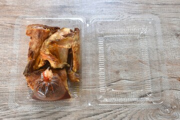 roasted chop chicken meat wing and leg dipping with spicy sauce in transparent plastic packaging on table