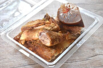 roasted chop chicken meat wing and leg dipping with spicy sauce in transparent plastic packaging on table