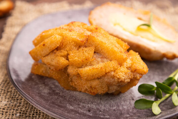 Chicken Schnitzel on gray plate with microgreen on brown wooden background and linen textile. side view, selective focus