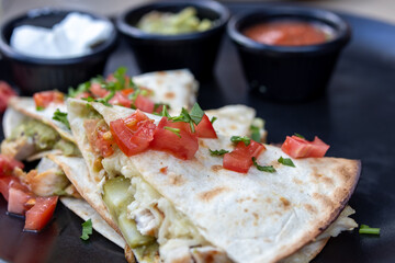 Delicious Chicken Quesadilla with Toppings on a Black Plate