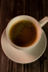 A cup of coffee on wooden table.View from above.Coffee with foam.Vertical Photo