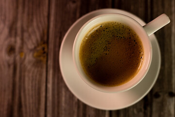 A cup of coffee on a wooden table. View from above. Coffee with foam