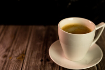 A white bowl with aromatic coffee on a white saucer. Coffee with foam