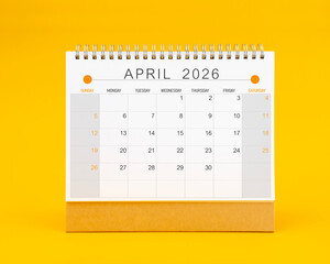 April 2026 desk calendar on yellow background, Front view.