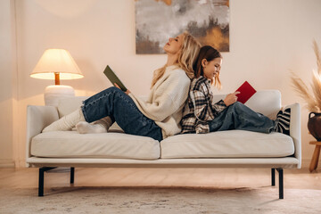 Reading the literature. Mother and daughter are together in domestic room