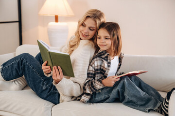 Reading the literature. Mother and daughter are together in domestic room