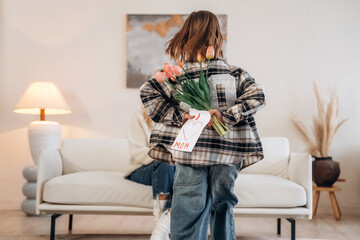 Surprise, mother's day, flowers. Woman and daughter are together in domestic room
