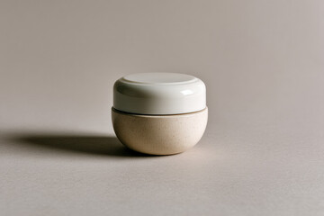 A blank white cosmetic cream jar sits elegantly on a neutral background casting soft shadows, emphasizing minimalism and simplicity in skincare packaging