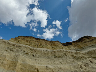 Rocky hillside with a blue sky in the background. The sky is partly cloudy. The hillside is covered in rocks and dirt