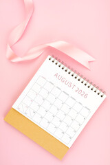 August 2026 desk calendar with pink ribbon, Flat lay.