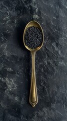 Black Poppy Seeds in Antique Spoon on Dark Stone