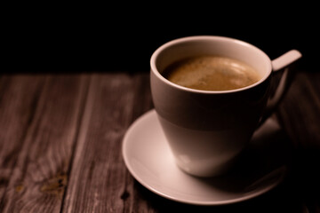 Aromatic strong coffee on the table. White Cup with Coffee on a Black Background