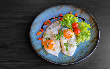 fried eggs on a blue plate lettuce leaf and cherry tomatoes