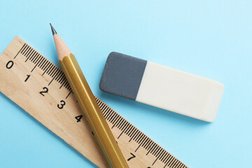 Eraser, pencil and ruler on light blue background, top view