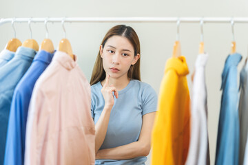 Choose clothes, girl try on apparel, worry choosing dress, nothing to wear. Attractive asian young...