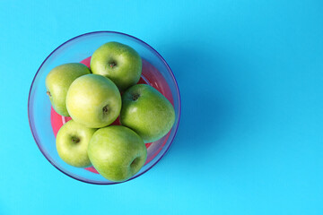 Kitchen scale with apples on light blue background, top view. Space for text