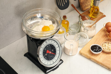 Retro mechanical kitchen scale and different food products on white marble countertop indoors