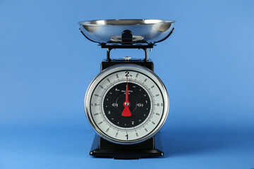 Mechanical kitchen scale with bowl on blue background