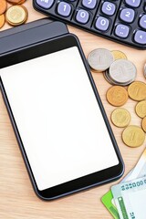 Mobile payment terminal with blank screen, coins, credit cards, calculator on wood surface. Enhance ecommerce business efficiency today.