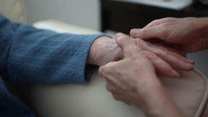 A caregiver gently holds the hand of an elderly woman, providing comfort and connection in a healthcare facility. This intimate moment fosters engagement and care.