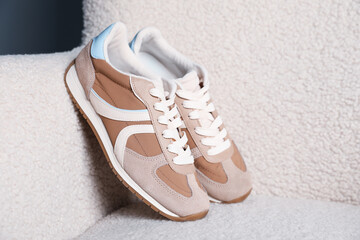 Pair of stylish sneakers on light armchair