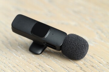Lavalier microphone on wooden table, closeup. Audio equipment