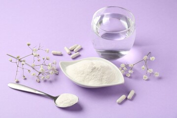 Collagen powder in bowl, spoon, pills, glass of water and gypsophila flowers on violet background