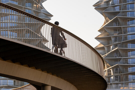 Bicycle commuter riding through curved urban bridge in Copenhagen, Denmark, reflecting future mobility, urban balance and sustainable architectural integration.