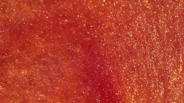 liquid with dissolved particles of red orange candurin and bubbles slowly moves and shines. abstract bright background