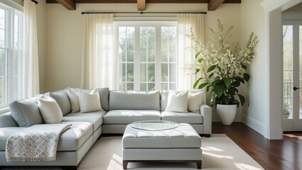 An open, airy living room with light gray furniture, a large plant, and lots of natural light