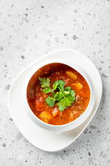 A hearty bowl of beef stew, featuring tender meat, potatoes, and tomatoes, garnished with fresh cilantro. This comforting dish is perfect for warming up on a chilly day or enjoying a satisfying meal.