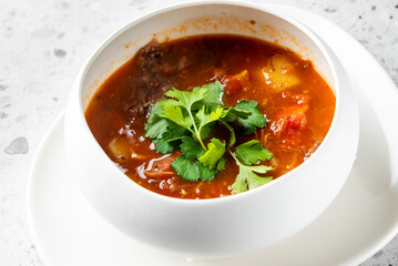 A hearty bowl of beef stew, featuring tender meat, potatoes, and tomatoes, garnished with fresh cilantro. This comforting dish is perfect for warming up on a chilly day or enjoying a satisfying meal.