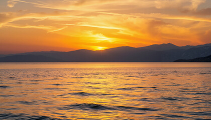 Fototapeta premium Sunset over tranquil waters with distant mountains 