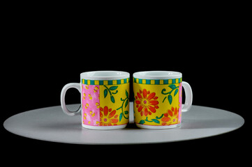 two mugs on a white stand on a black background