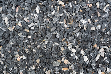 Close-up texture of crushed black and white gravel stones, perfect for construction or landscaping backgrounds.