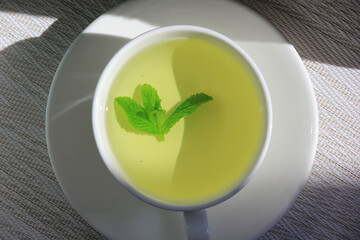 White cup and saucer with mint tea