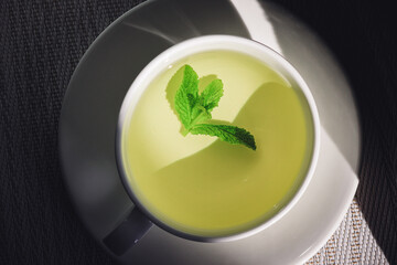 White cup and saucer with mint tea