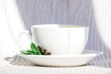 Fototapeta premium White cup and saucer with mint tea