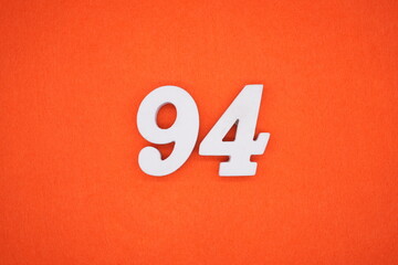 The numbers are made of white painted wood placed on an orange paper background.